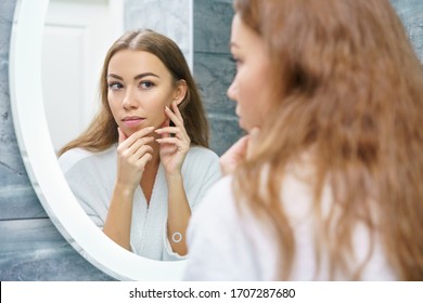 Beautiful Young Woman Looks At Her Face In The Mirror