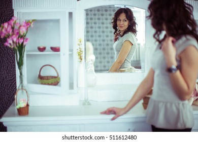 beautiful young woman looks at herself in the mirror