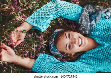 Beautiful young woman lying down in the flowery grass and enjoying sunny spring day.