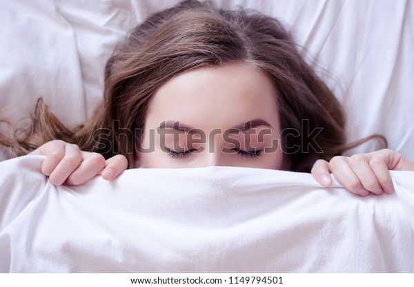 美しい若い女性がベッドに横になって寝ている 目を閉じた十代の女の子は 朝白い毛布で顔を覆う 睡眠のコンセプトが足りない 上から見る スペースをコピーします の写真素材 今すぐ編集