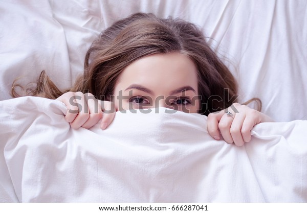 美しい若い女性がベッドに横になって寝ている 目を開けた10代の女の子は 朝白い毛布で顔を覆う 睡眠のコンセプトが足りない 上から見る スペースをコピーします の写真素材 今すぐ編集