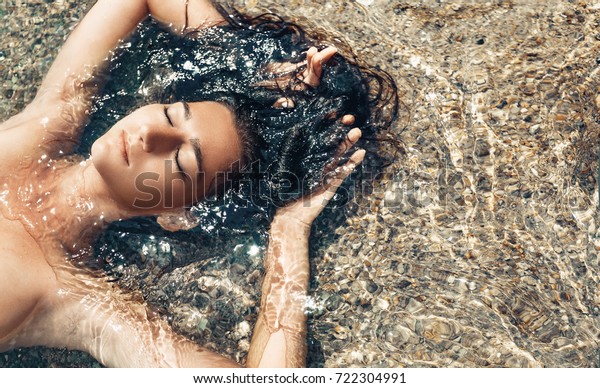 Attractive Woman Lying Down On Beach By The Ocean Using A 