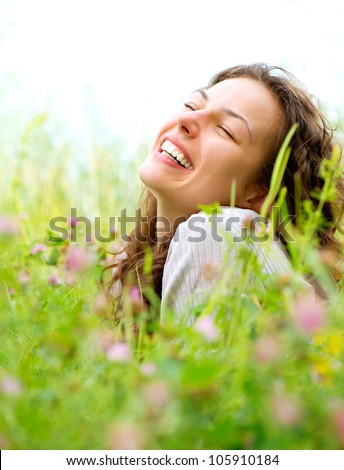 Beautiful Young Woman lying in Meadow of Flowers. Enjoy Nature