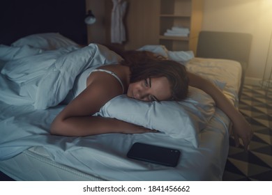 Beautiful young woman lying on her stomach on bed, unable to sleep, insomnia or anxiety due to stress