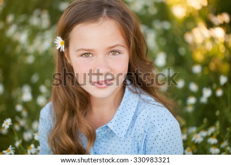 Beautiful young woman lying on grass and smelling flower, against background of summer green park.