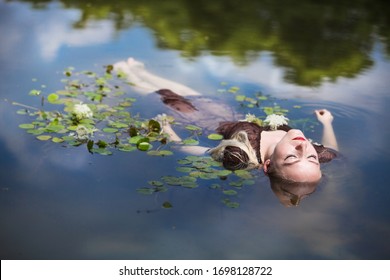 Beautiful young woman lying in the water with water lilies and lotus.