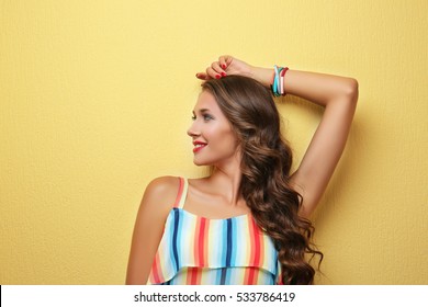 Beautiful young woman with make up and long  wavy hair on color background