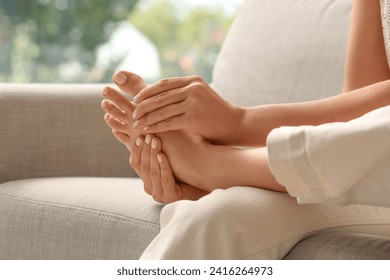 Beautiful young woman making foot massage on sofa in living room at home - Powered by Shutterstock