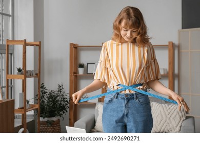 Beautiful young woman measuring her waist at home. Weight loss concept - Powered by Shutterstock