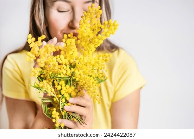 Beautiful young woman with mimosa flowers on white background. Close up