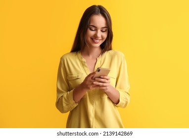 Hermosa joven con teléfono móvil de fondo amarillo
