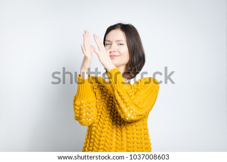 beautiful young woman mocks you, isolated on gray background