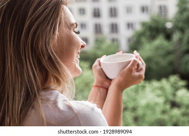 Beautiful young woman on a balcony enjoing morning with cup of tea - Powered by Shutterstock