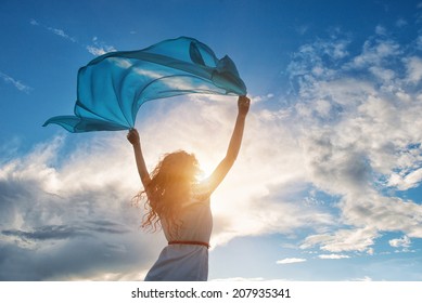 Beautiful young woman on sunset background with blue tissue.
