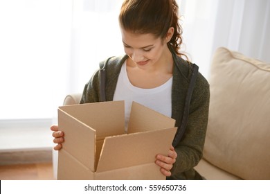 Beautiful Young Woman Opening Box With Parcel At Home