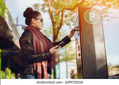 beautiful young woman pays for Parking in meter on the street