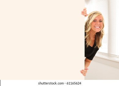 Beautiful Young Woman Peeking Out Behind Wall Of Office Or School Building.