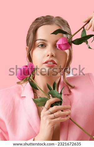 Beautiful young woman with peony flowers on pink background