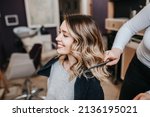 Beautiful young woman with perfect hairstyle satisfied after dyeing hair and making highlights in hair salon.