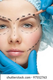 Beautiful young woman with perforation lines on her face before plastic surgery operation. Beautician touching woman face.