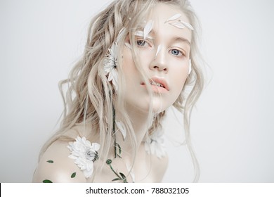 Beautiful young woman with petals of chrysanthemum on face and body. Beauty, natural cosmetics concept.