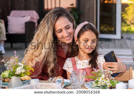 Beautiful young woman photographing with her adorable preteen daughter at family dinner
