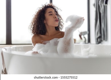 Beautiful young woman playing with foam in bath stock photo - Powered by Shutterstock