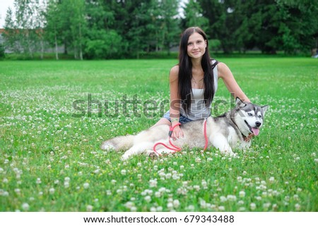 Beautiful young woman playing with funny husky dog outdoors at park