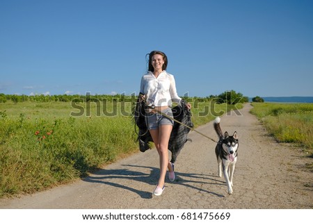 Beautiful young woman playing with funny husky dog outdoors at park. Summertime and sunset