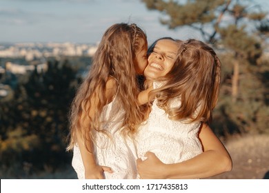 A Beautiful Young Woman Playing With Her Daughter. Happy Family Spends Their Day In The Nature. Three Blonde Females, Mother With Her Two Little Kids.