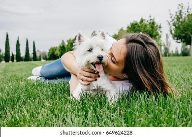 Beautiful young woman playing with her little west highland white terrier in a park outdoors. Lifestyle portrait. - Powered by Shutterstock