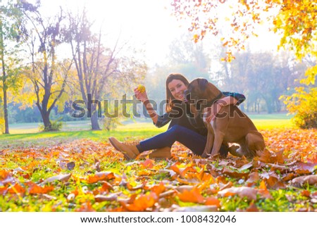 Beautiful young woman playing with her Dog in the Park in the autumn.