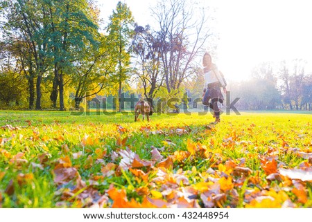 Beautiful young woman playing with her Dog in the Park in the autumn.