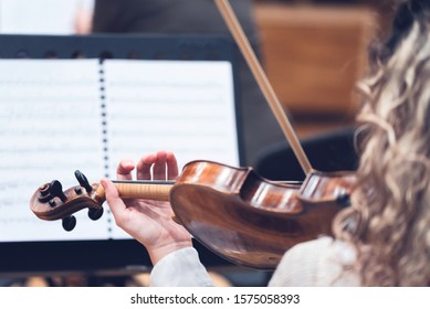 Beautiful Young Woman Playing The Violin.  Sheet Music In Background