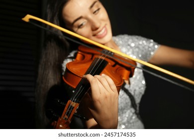 Beautiful young woman playing violin in dark room, closeup - Powered by Shutterstock