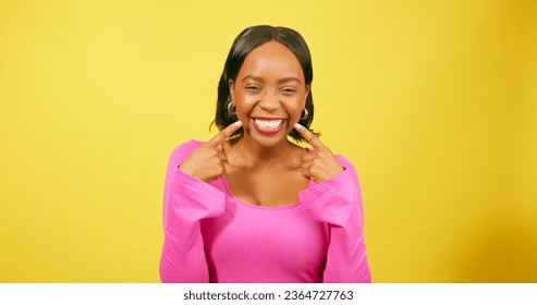 Beautiful young woman points to smile, white teeth, happy in yellow studio - Shutterstock ID 2364727763