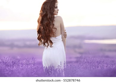Beautiful young woman portrait in lavender field. Attractive brunette girl with long curly hair style in white dress dreaming.  - Shutterstock ID 552878746