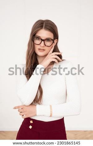 Beautiful young woman portrait wearing glasses to improve her eyesight. Beautiful wavy hair, daytime makeup, dressed in normal clothes in a bright interior