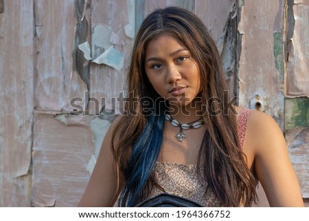 A beautiful young woman poses for camera infront of weatherd door.