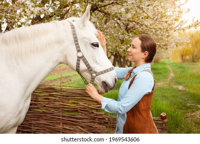 A Beautiful Young Woman Poses Next To A White Horse. Cowboy, Ranch, Village. Love Friendship Concern. Pet. Outside The Door, Green Grass Woods. Sunlight. Blurred Background, Screensaver Smile