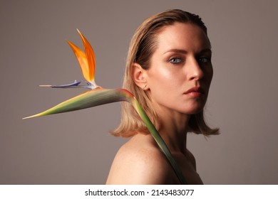 Beautiful Young Woman Posing With Bird Of Paradise Flower Indoor. Isolated.