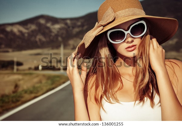 Beautiful young woman posing on a road over picturesque landscape.