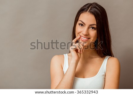 Beautiful young woman posing in the studio, expressing their emotions, looking at camera, on a gray background