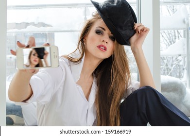 Beautiful young woman posing taking selfshot or selfy picture of herself on mobile device portrait