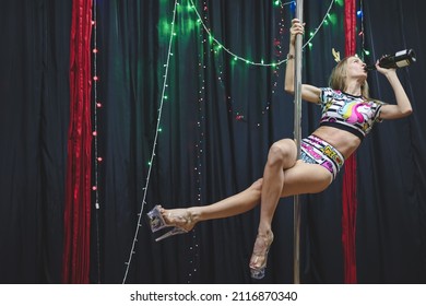 Beautiful young woman posing while dancing on pylon. Pole dancer in new year’s outfit. Celebration New Year, girl's party.