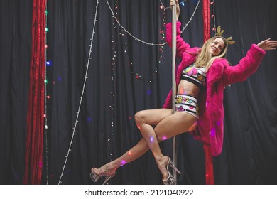 Beautiful young woman posing while dancing on pylon. Pole dancer in new year’s outfit. Celebration New Year, girl's party.