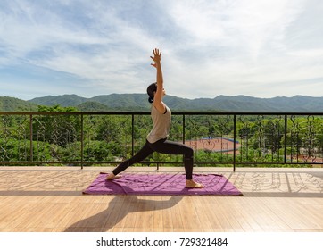 Beautiful young woman practices yoga in the midst of nature. Outdoor yoga warrior pose.