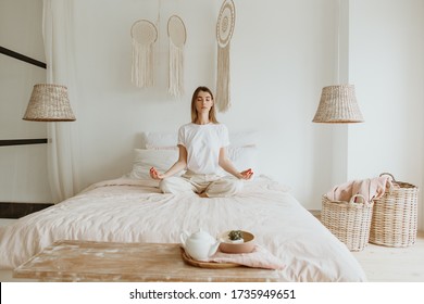 Beautiful young woman practicing meditation on the bed. - Powered by Shutterstock