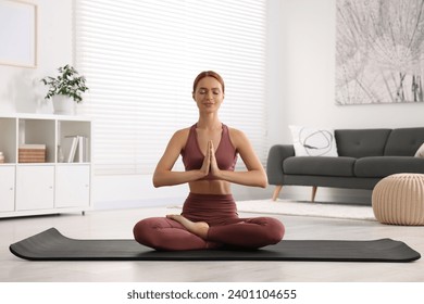 Beautiful young woman practicing Padmasana on yoga mat at home. Lotus pose - Powered by Shutterstock