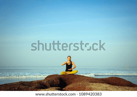 Beautiful young woman practicing yoga and stretching exercises at the summer tropic ocean  seashore